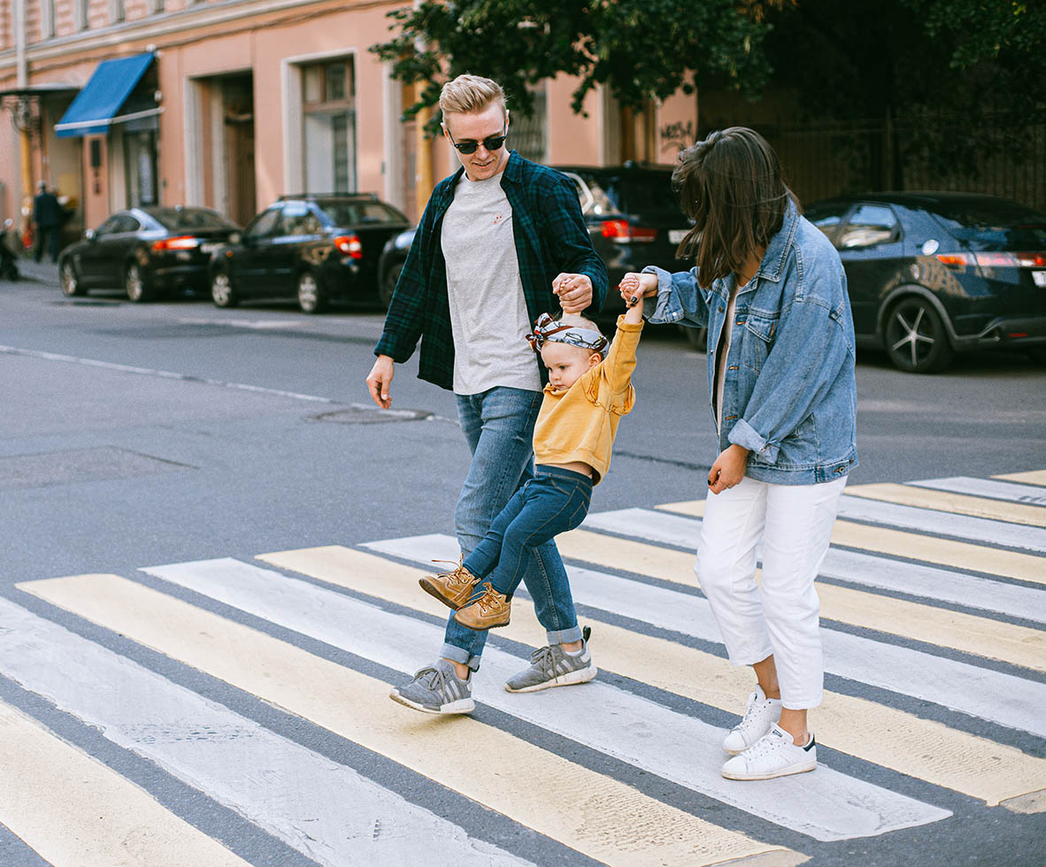 Family with young child walking in crosswalk.